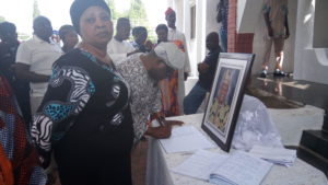Mrs Modupe-Adeleke Sani standing while Prof Isaac Folorunso signs the condolence register.