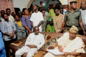 Ogbeni Rauf Aregbesola (right) Signing the condolence Register of the late Permanent Secretary, the husband of the deceased Mr Kolawole Awotunde (left), during the Condolence Visit to the families at their Residents in Ofatedo on Saturday 